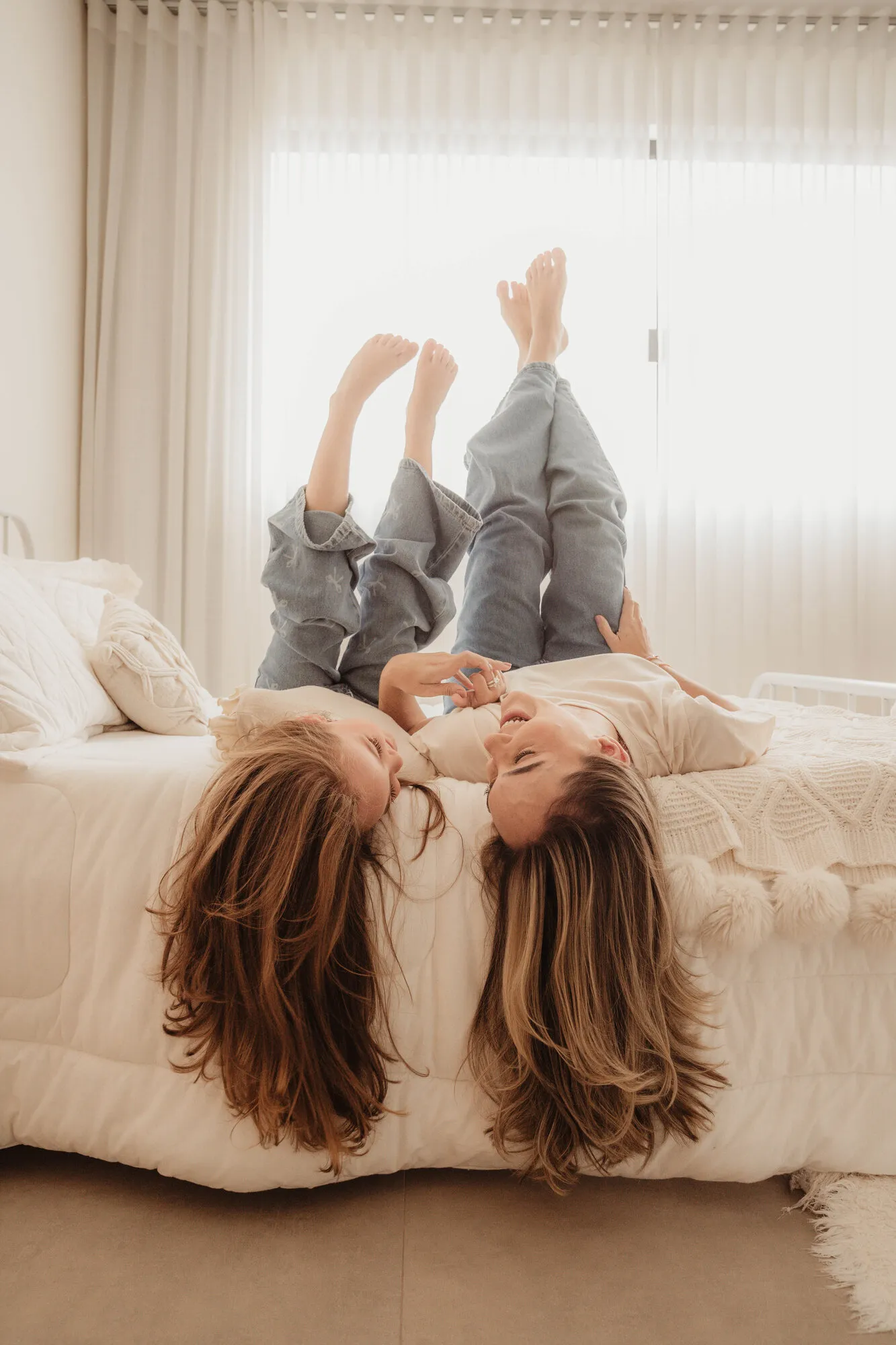 Crianças brincando de pernas para o ar na cama durante ensaio de família