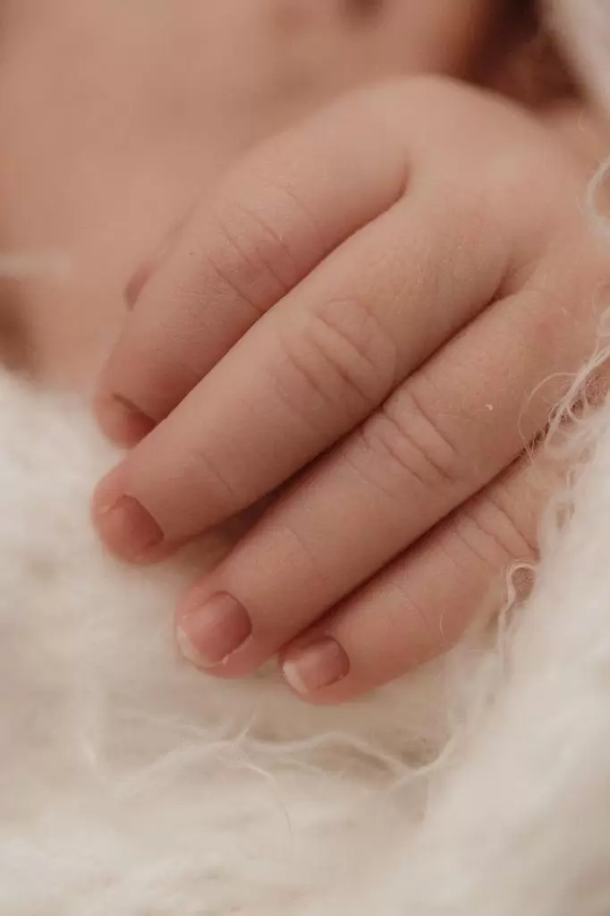 Mãozinha de recém-nascido em close, com os dedinhos encolhidos
