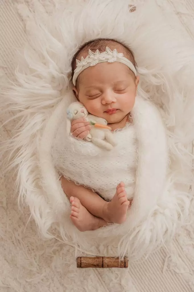 Recém-nascida com headband delicada em tons suaves durante ensaio newborn